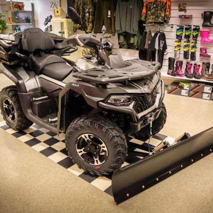 Sølvgrå ATV med plog i front inne i butikklokale