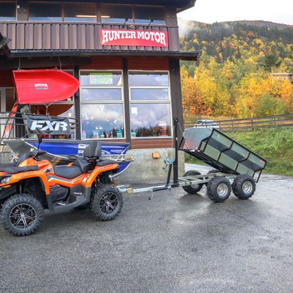 Oransje ATV med henger utenfor butikklokale